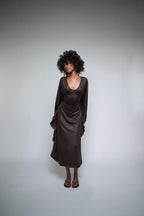Woman wearing a brown dress against a plain background