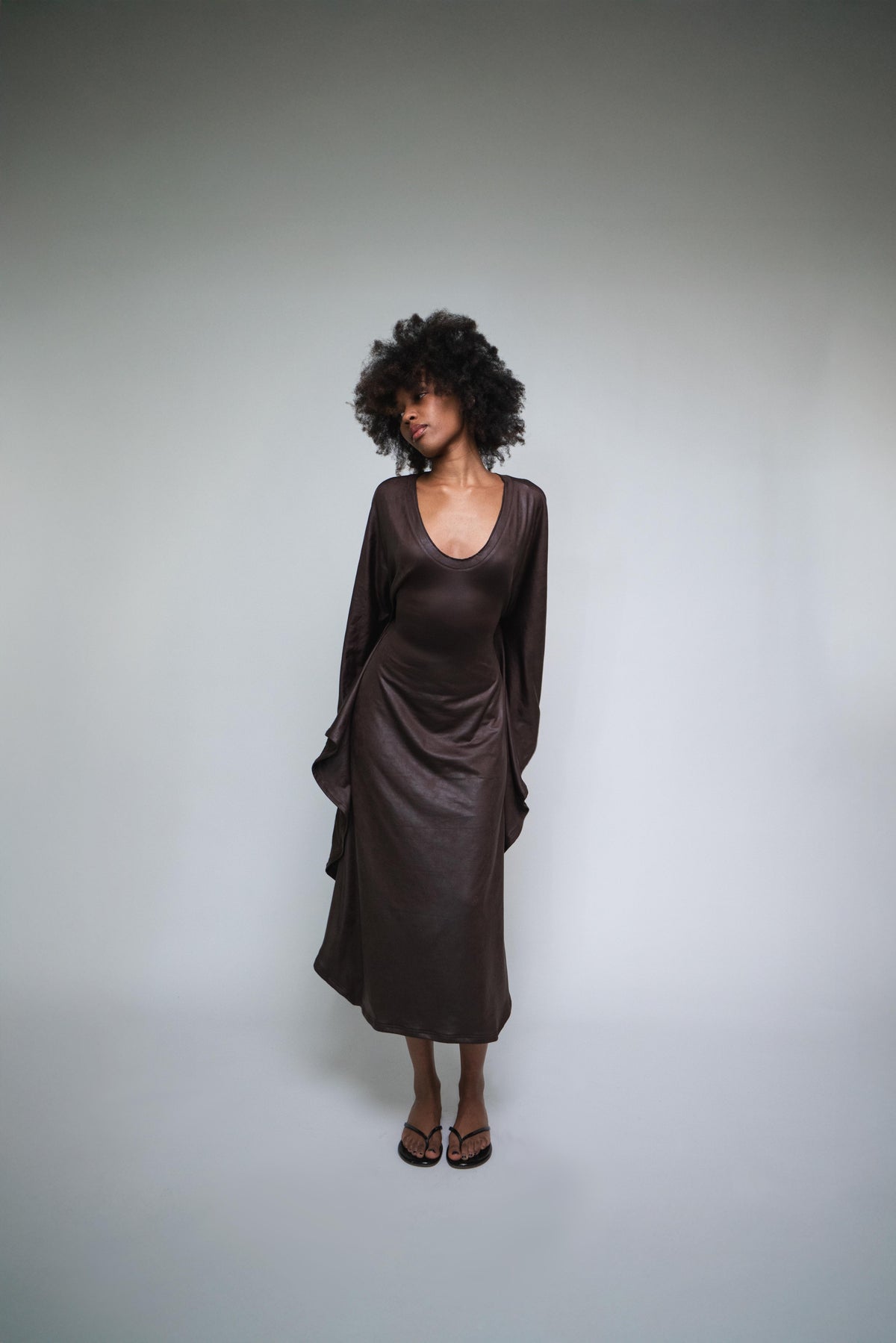 Woman wearing a brown dress against a plain background