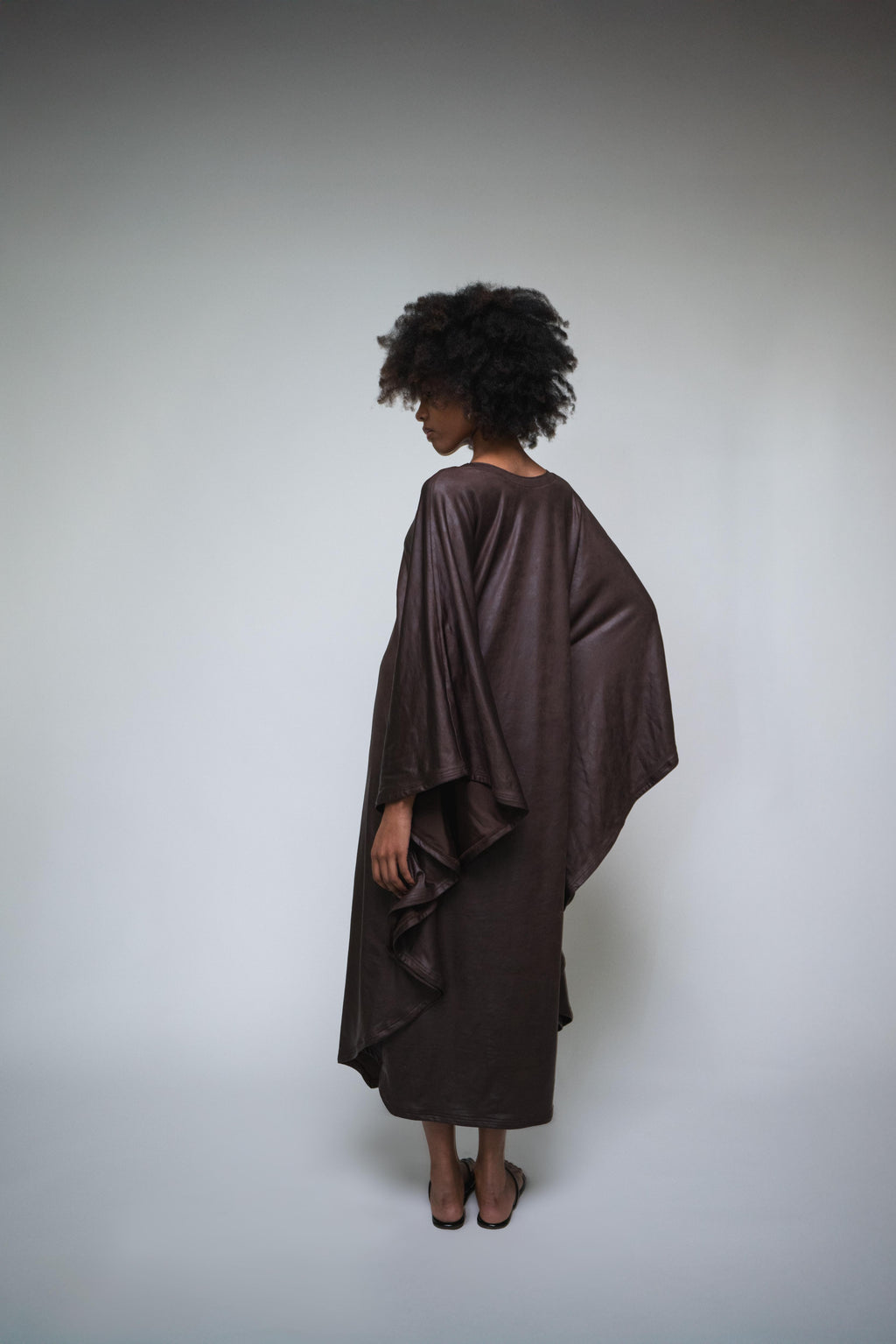 Person wearing a brown poncho against a plain background