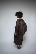 Person wearing a brown poncho against a plain background