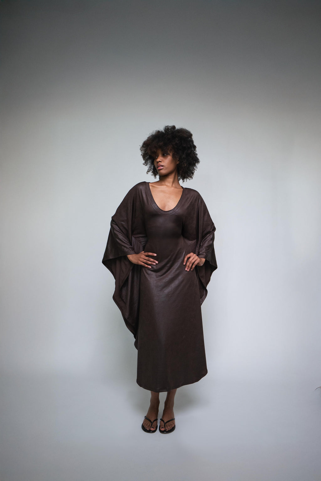 Woman wearing a brown satin dress against a gray background