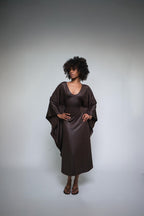 Woman wearing a brown satin dress against a gray background
