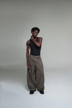 Person wearing a black tank top and plaid pants on a plain background