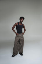 Man wearing a black tank top and plaid pants against a plain background