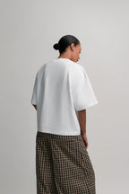 Person wearing a white t-shirt and plaid pants on a plain background