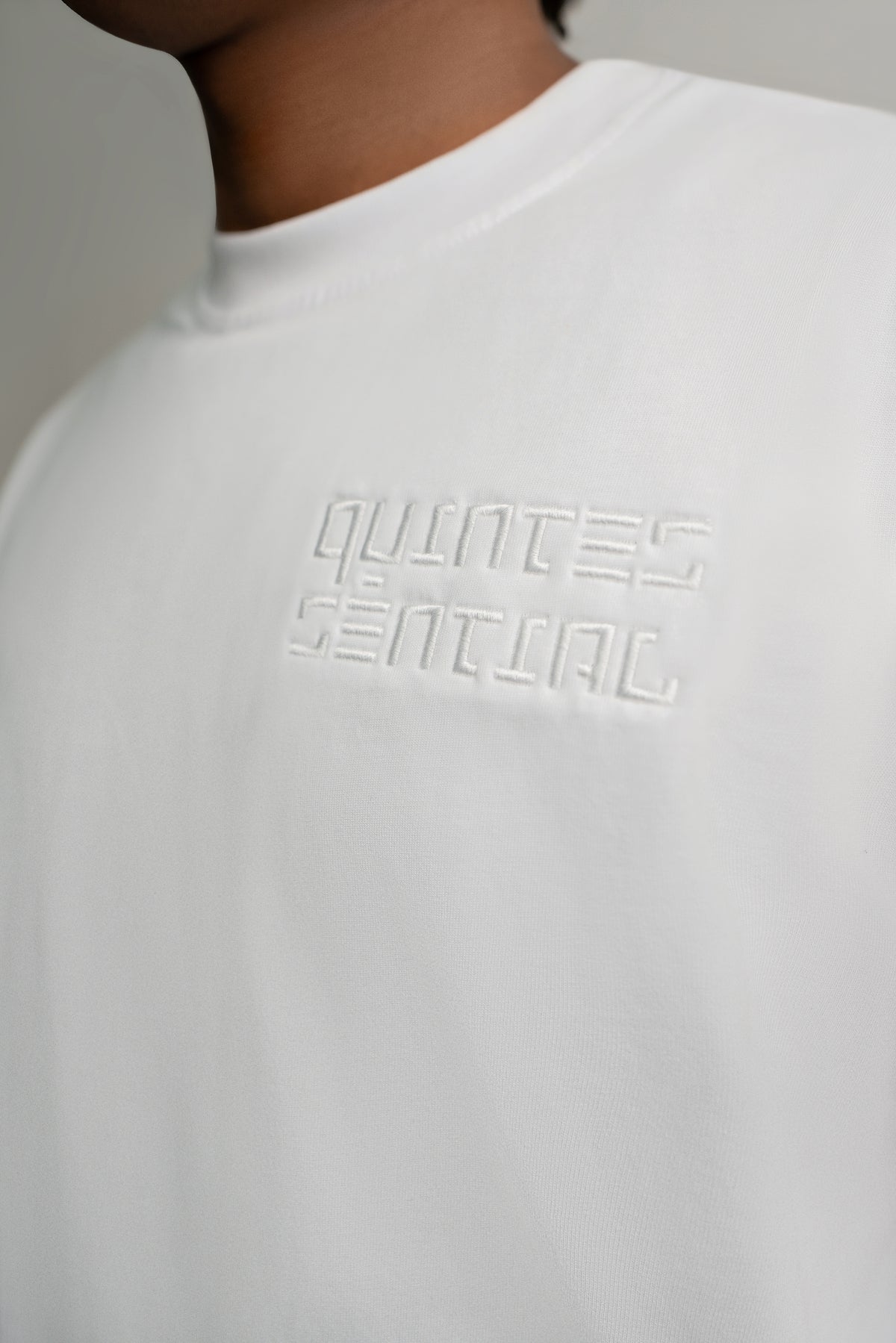 White sweatshirt with 'QUINTESENTHAL' text on a plain background