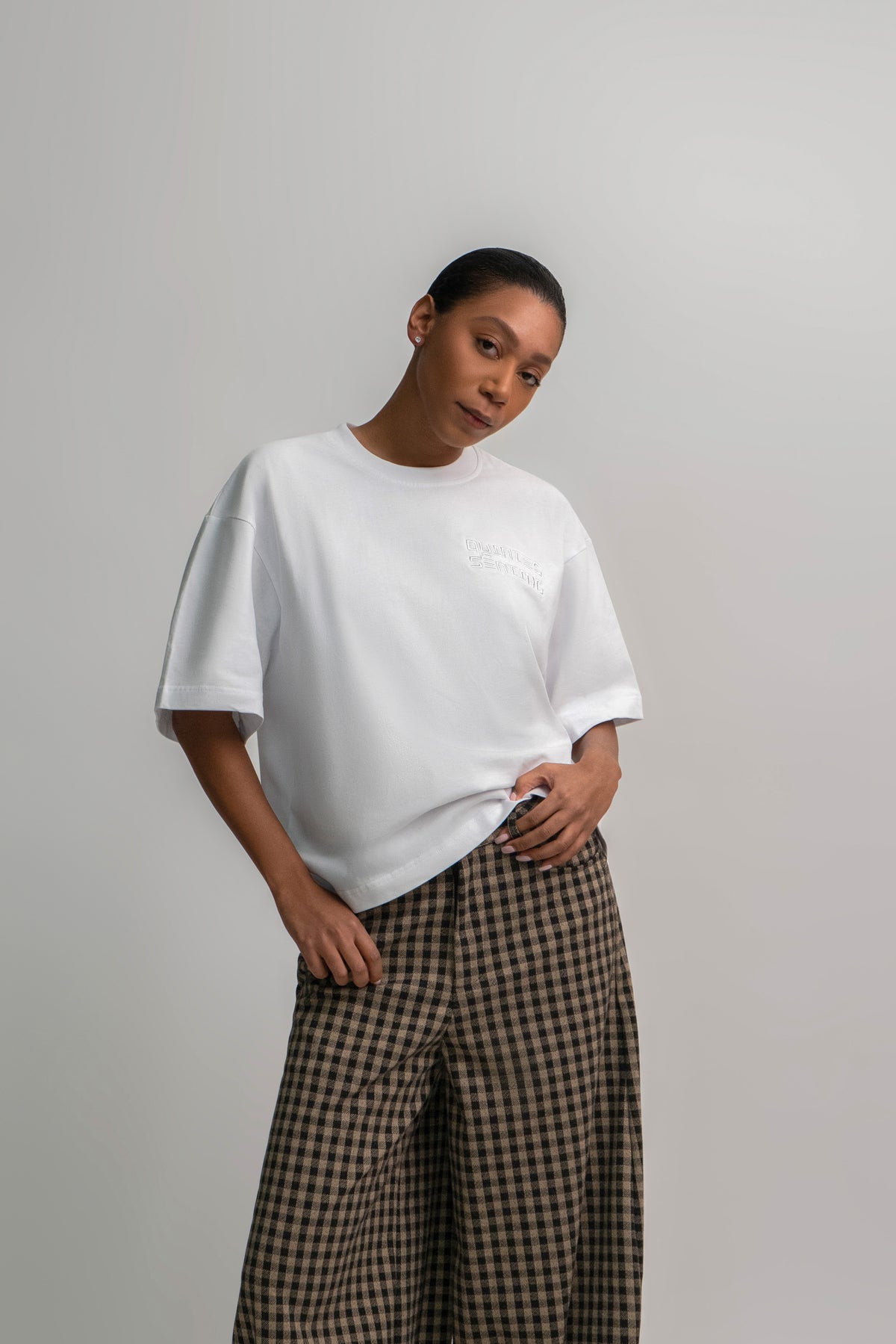 Person wearing a white t-shirt and checkered pants on a plain background
