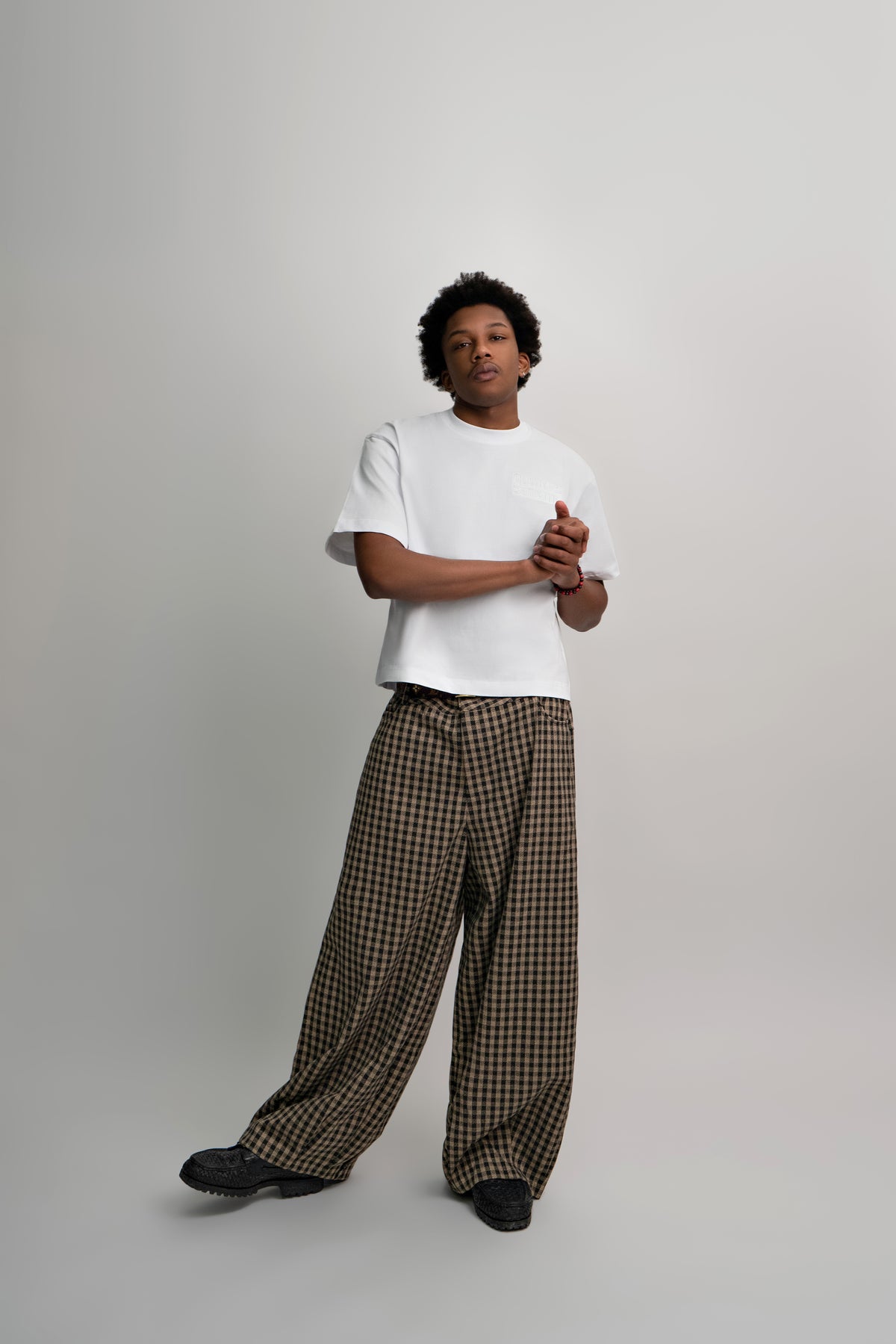 Person wearing a white t-shirt and checkered pants on a plain background